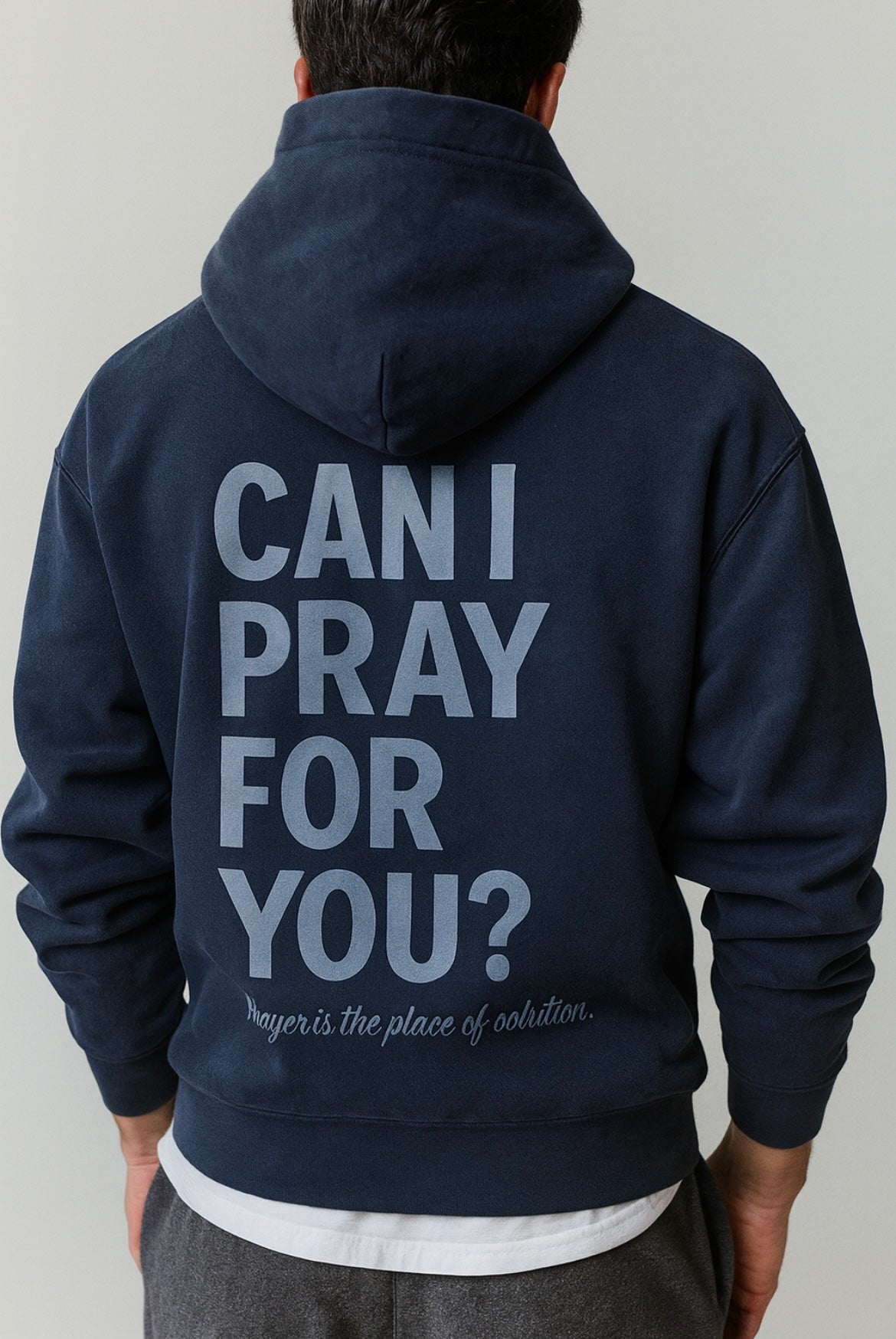 Navy blue hoodie with text on the back worn by a person, on a plain background